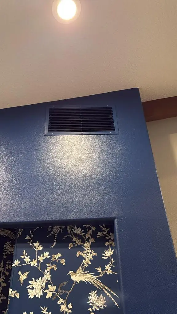 Close-up of a custom home interior design detail by Evolve Design at the SW 14th St project in Gresham, Oregon. Features a deep blue painted accent wall with an integrated ceiling vent, complementing a dark blue floral and bird pattern wallpaper inset
