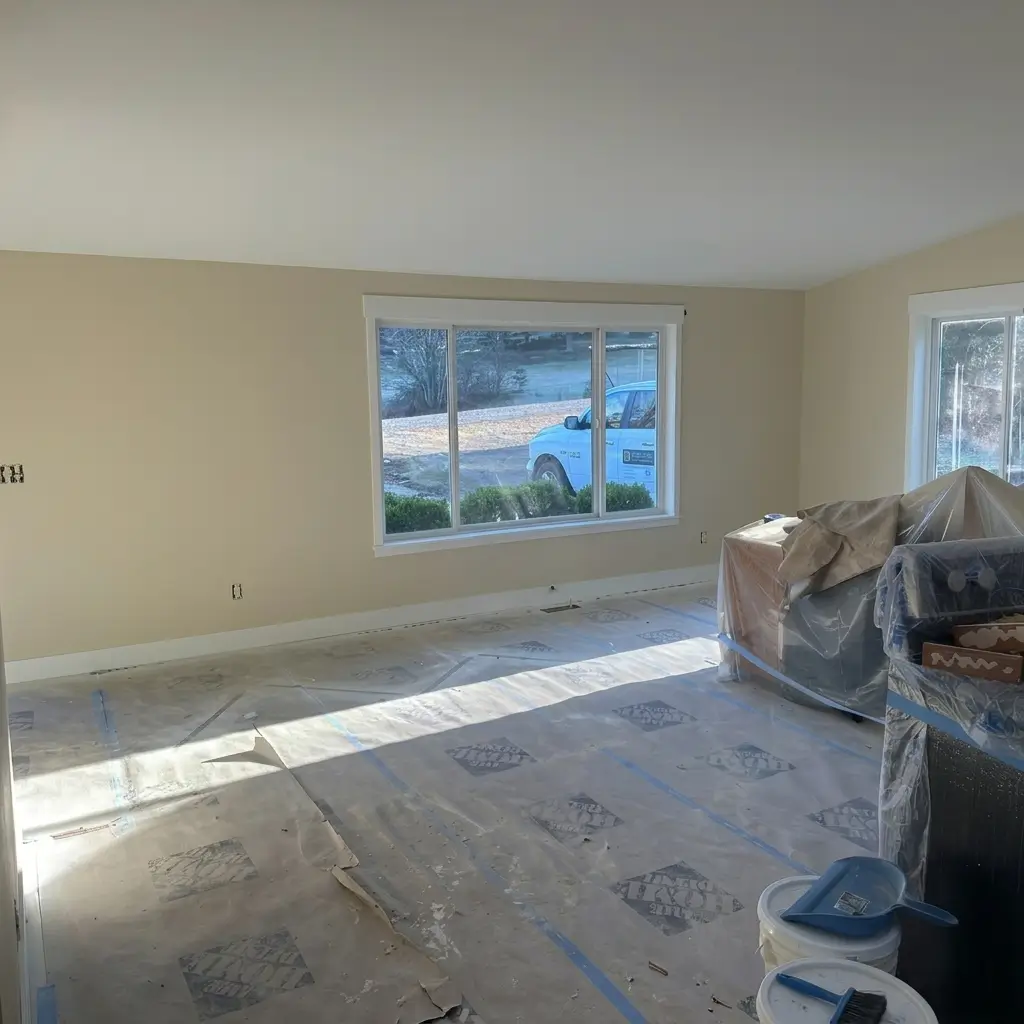Freshly painted warm beige interior room during a renovation with floor paper protection, covered furniture, and white trim molding in Woodland, Washington