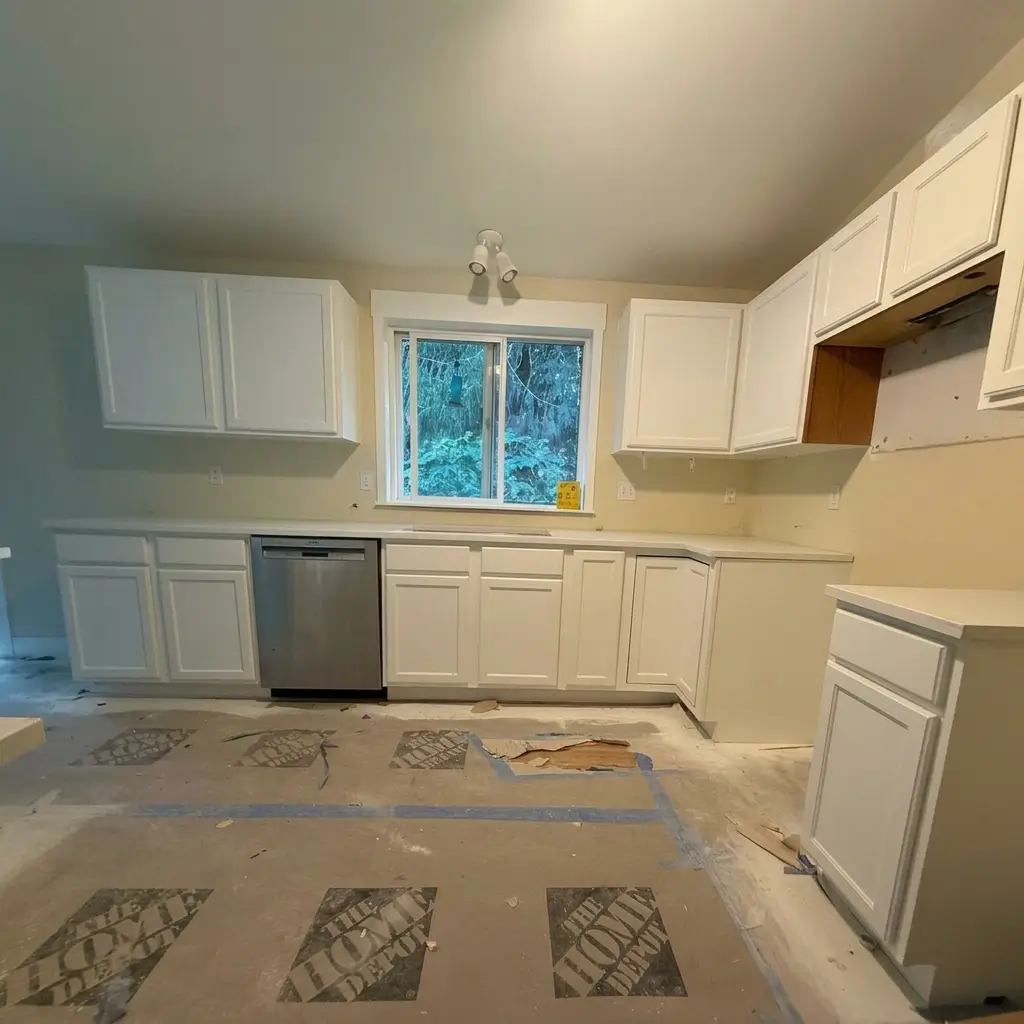 In-progress kitchen renovation showing newly installed white quartz countertops and white shaker cabinets with floor protection paper in Woodland, Washington