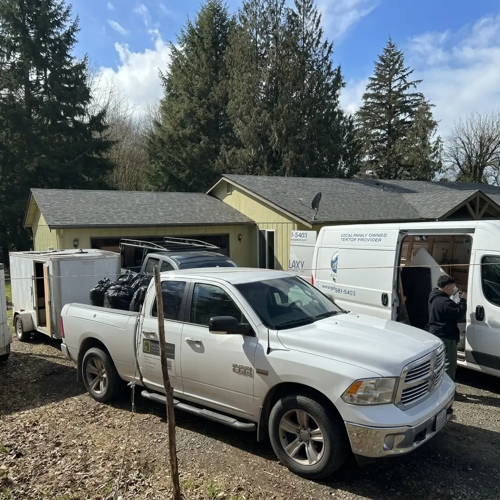 Work trucks, enclosed equipment trailer, and trade partner delivery vans parked in front of a residential home during a remodeling project in Woodland, Washington
