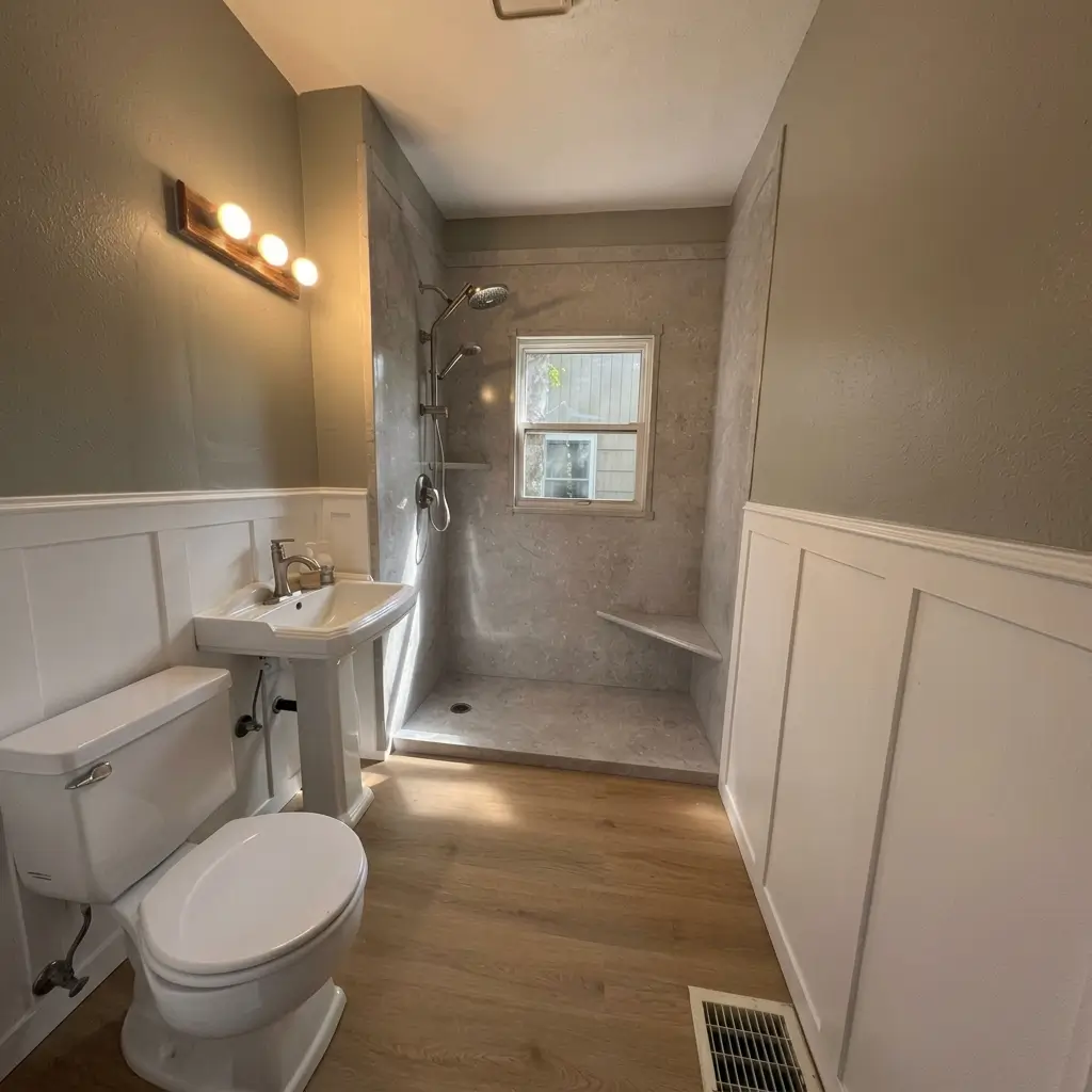 Bright remodeled bathroom featuring a walk-in tiled shower with built-in corner bench, white wainscoting wall paneling, pedestal sink, and wood-look flooring in Portland, Oregon